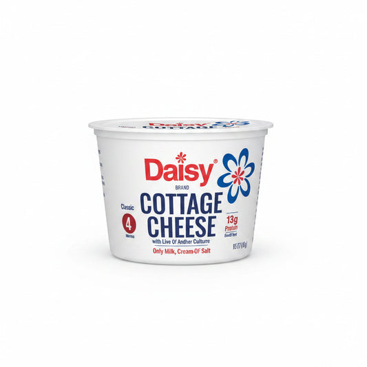 Hand holding a container of Daisy cottage cheese in a kitchen setting